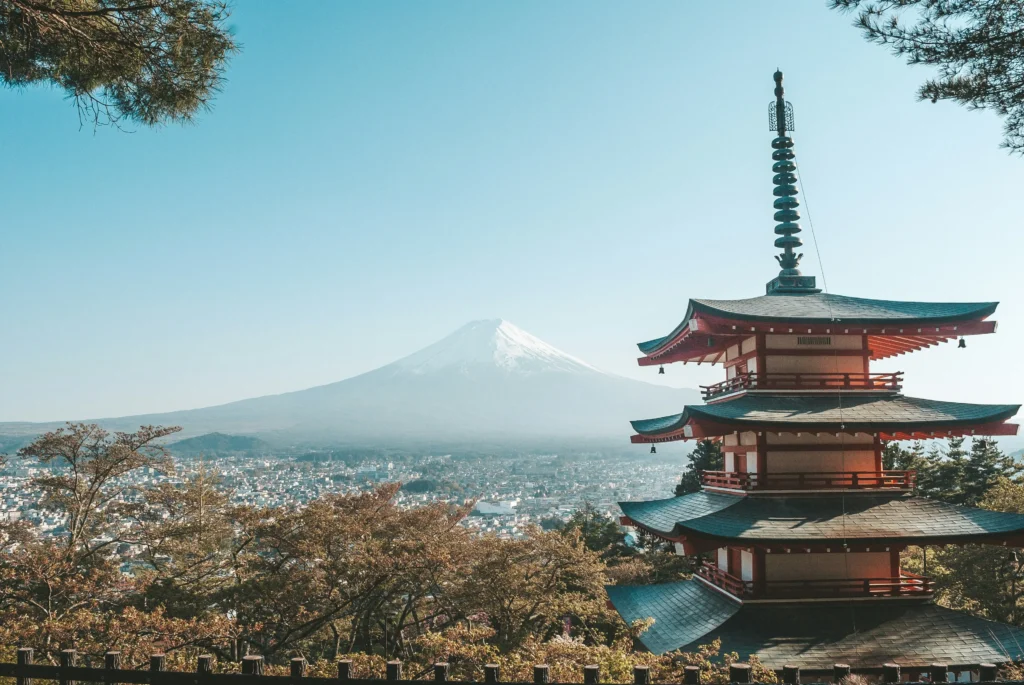Five-story Chureito Pagoda overlooking Fujiyoshida with snow-capped Mount Fuji beyond on a clear blue morning.