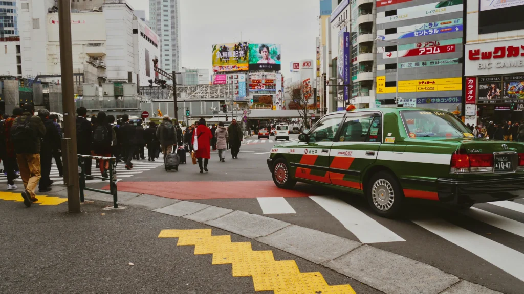 Green taxi and pedestrians at Shibuya Crossing in Tokyo