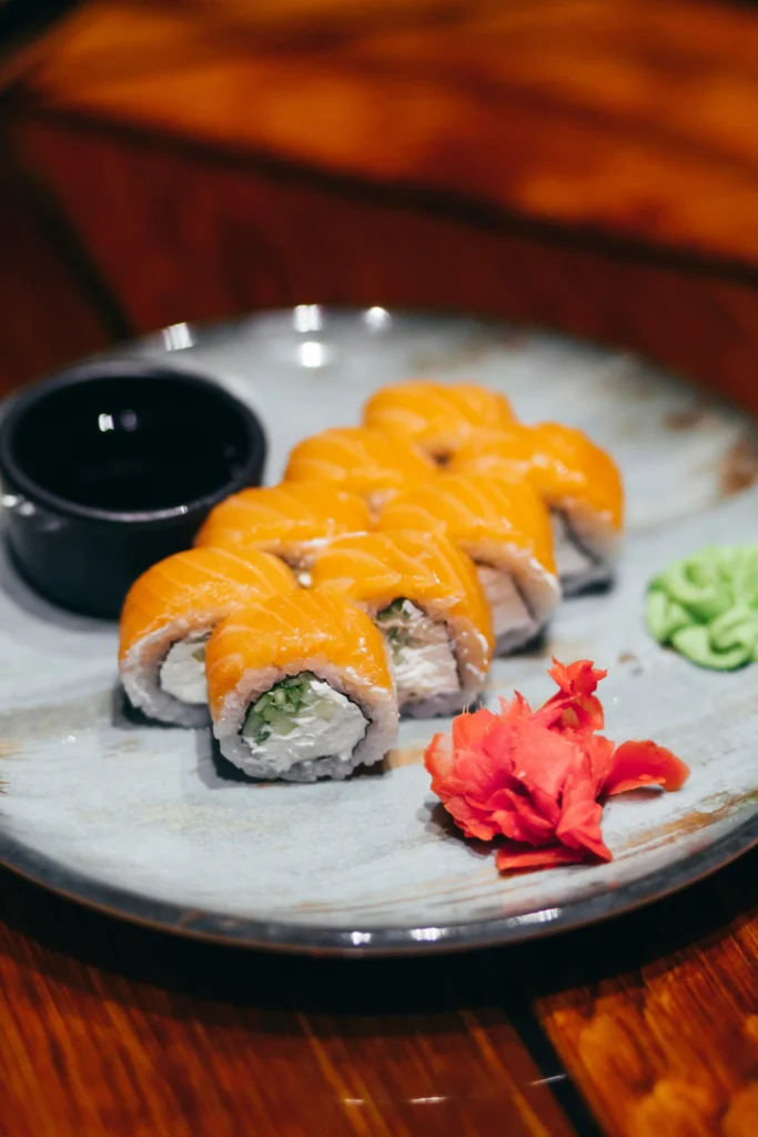 Salmon sushi rolls with wasabi, ginger, and soy sauce on a plate.